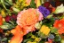A very colorful bouquet of flowers featuring an orange centerpiece accented by red roses and more!